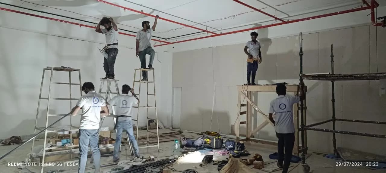 ESEA team on ladders and scaffolding wiring a large commercial hall